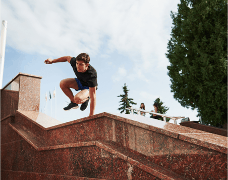 Young man jumping over an outdoor staircase wall