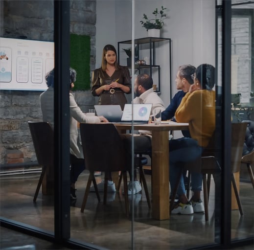 A team of professionals in a meeting, discussing ideas in a modern conference room with a presentation screen.