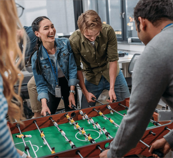 A group of people enjoy a game of table soccer in a very jovial and friendly atmosphere.