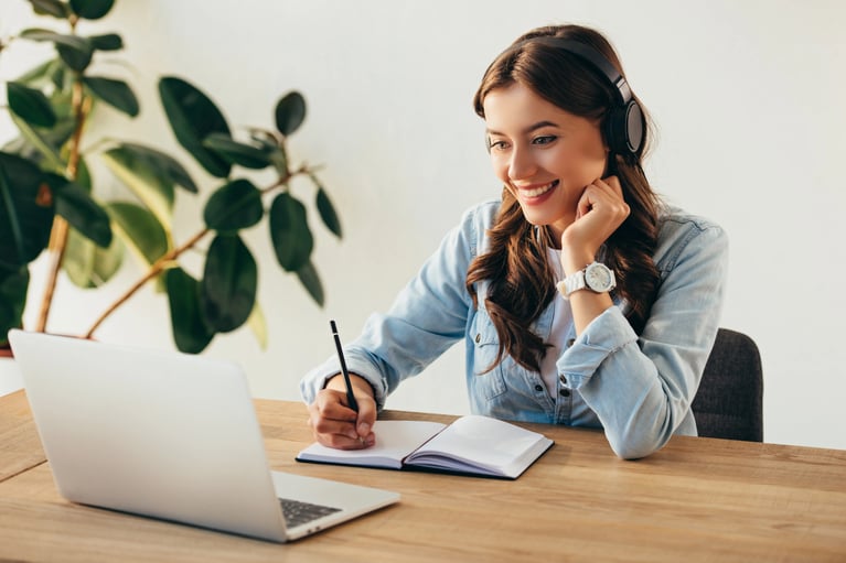 Portrait of a smiling young woman following a lesson about digital with headphones taking part in an office training session