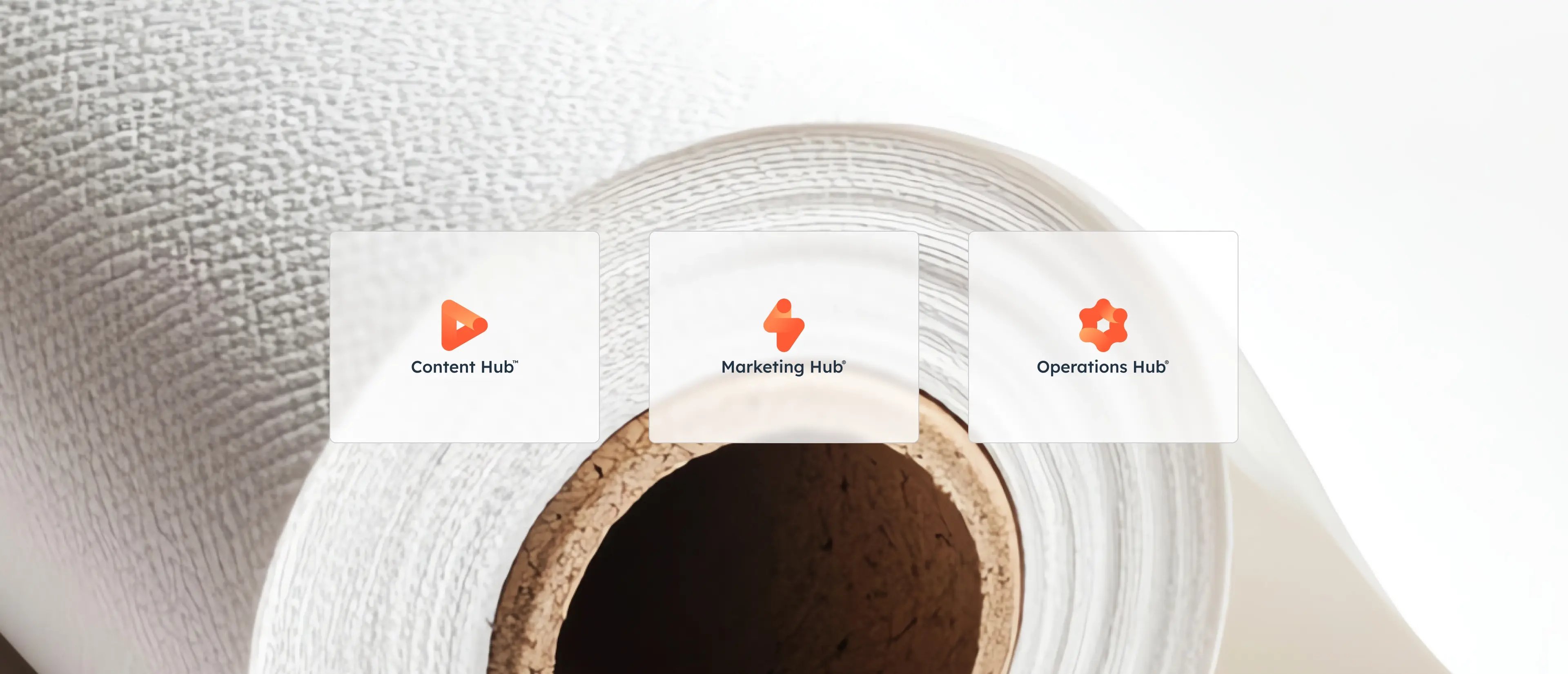 Three HubSpot hub icons: Content Hub, Marketing Hub and Operations Hub are displayed on a textured white paper background.